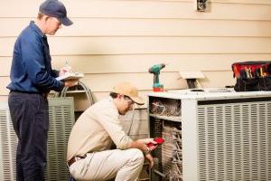 two-air-conditioning-techs-working-on-outdoor-unit